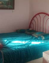 تخت خواب با روتختی سبز آبی و میز عسلی اتاق خواب خانه روستایی در ملاکلا